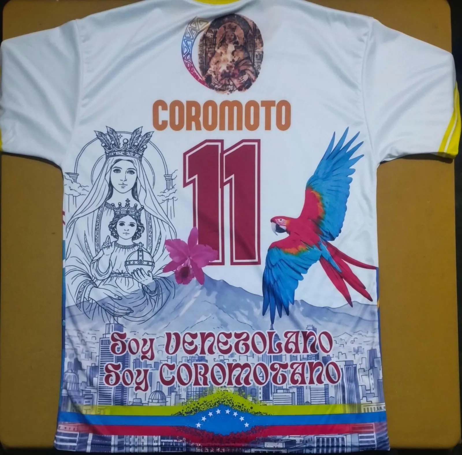 Franela de la Virgen de Coromoto con una guacamaya, en blanco y colores