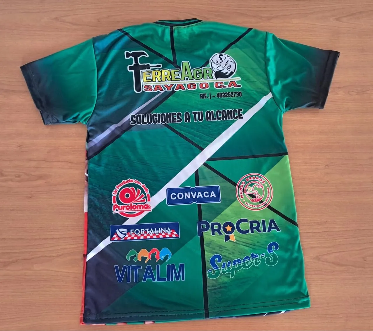 Franela verde de una ferretería con los logos de sus patrocinantes