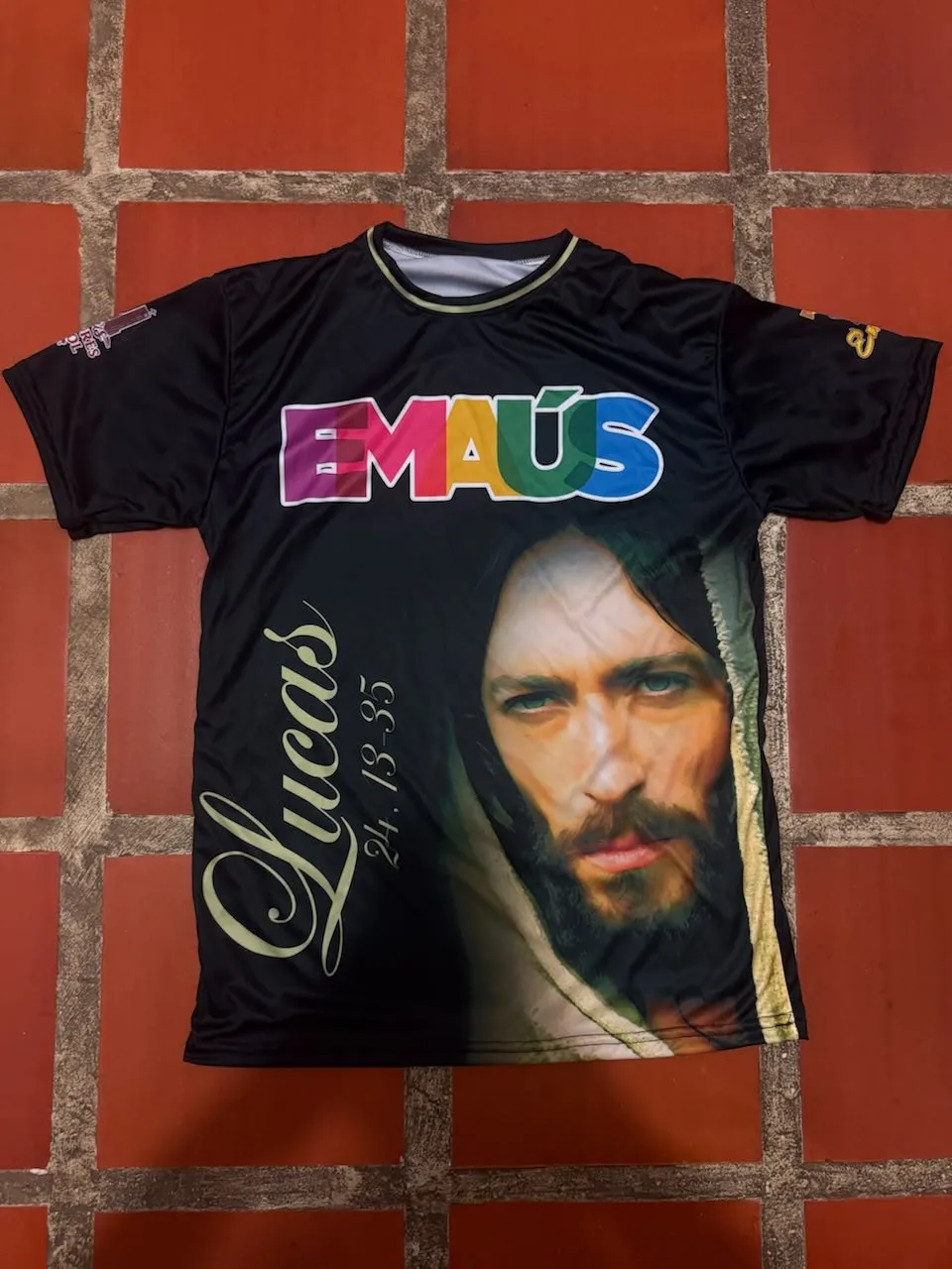 Franela negra con una imagen religiosa y texto en dorado